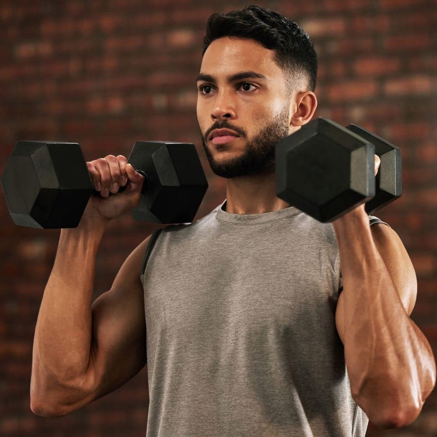 Man pressing a pair of hex dumbbells at shoulder height